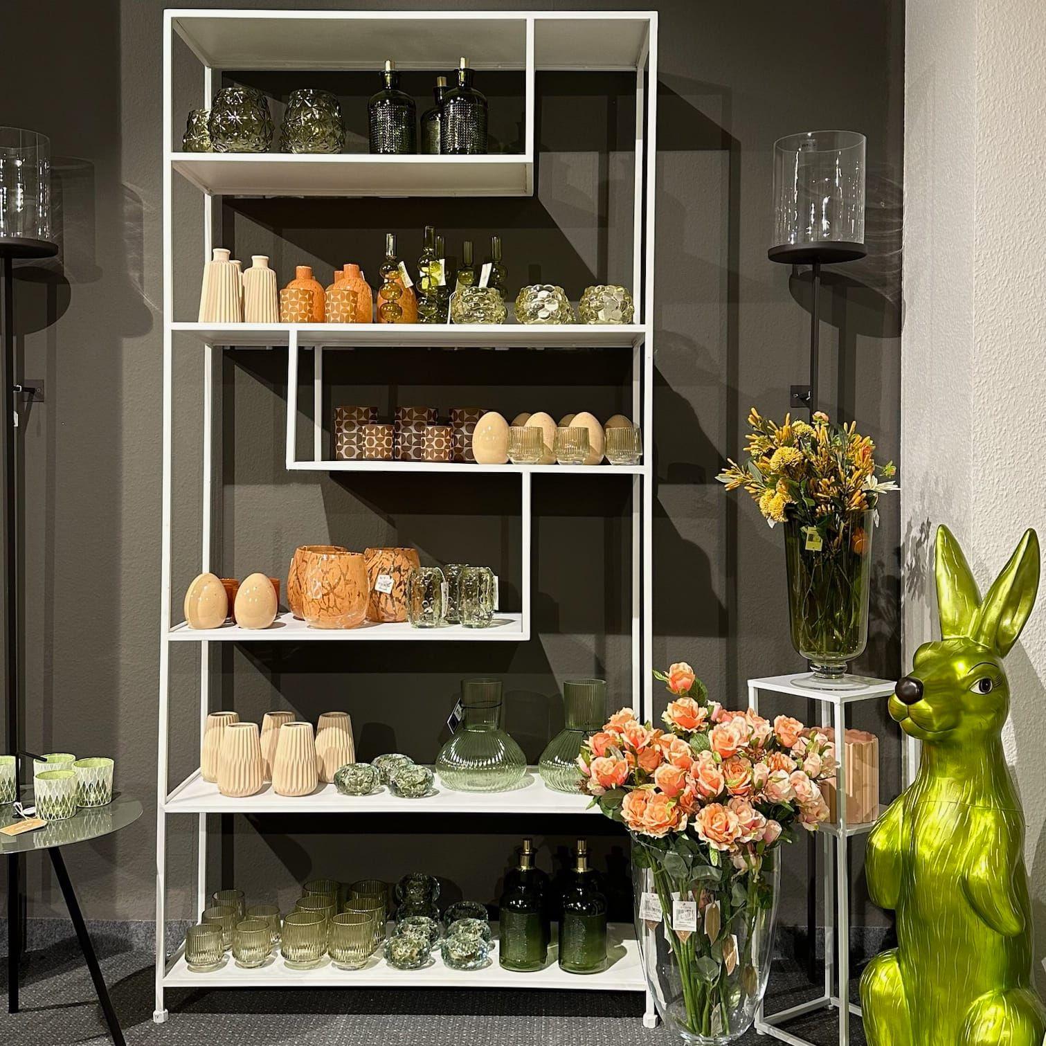 Elegantes Regal mit grünen Glasvasen, Windlichtern und Frühlingsblumen - moderne Frühjahrsdeko bei Möbel Grell.