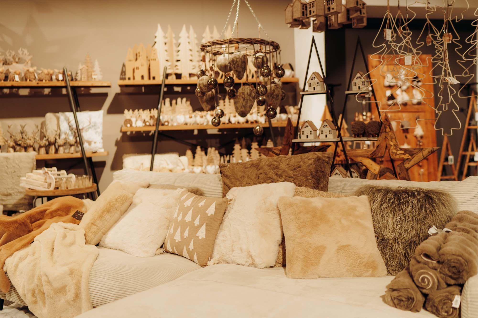 Kuschelige Wohnzimmer-Ecke mit beigen Kissen, Weihnachtsdeko und liebevoll arrangierten Holzaccessoires.