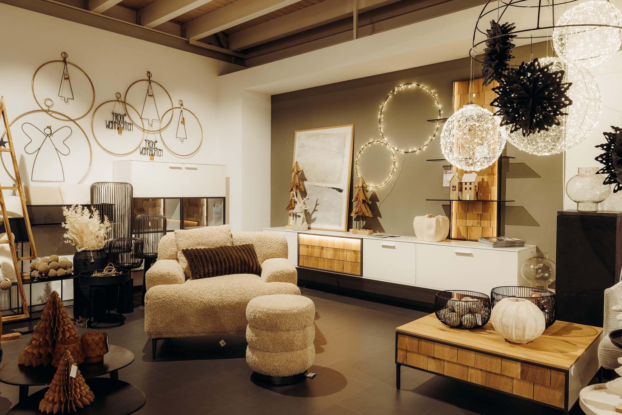 Stilvolle Wohnzimmer-Ausstellung mit Bouclé-Sessel, LED-Lichtringen und modernen Holzmöbeln in warmer Atmosphäre.