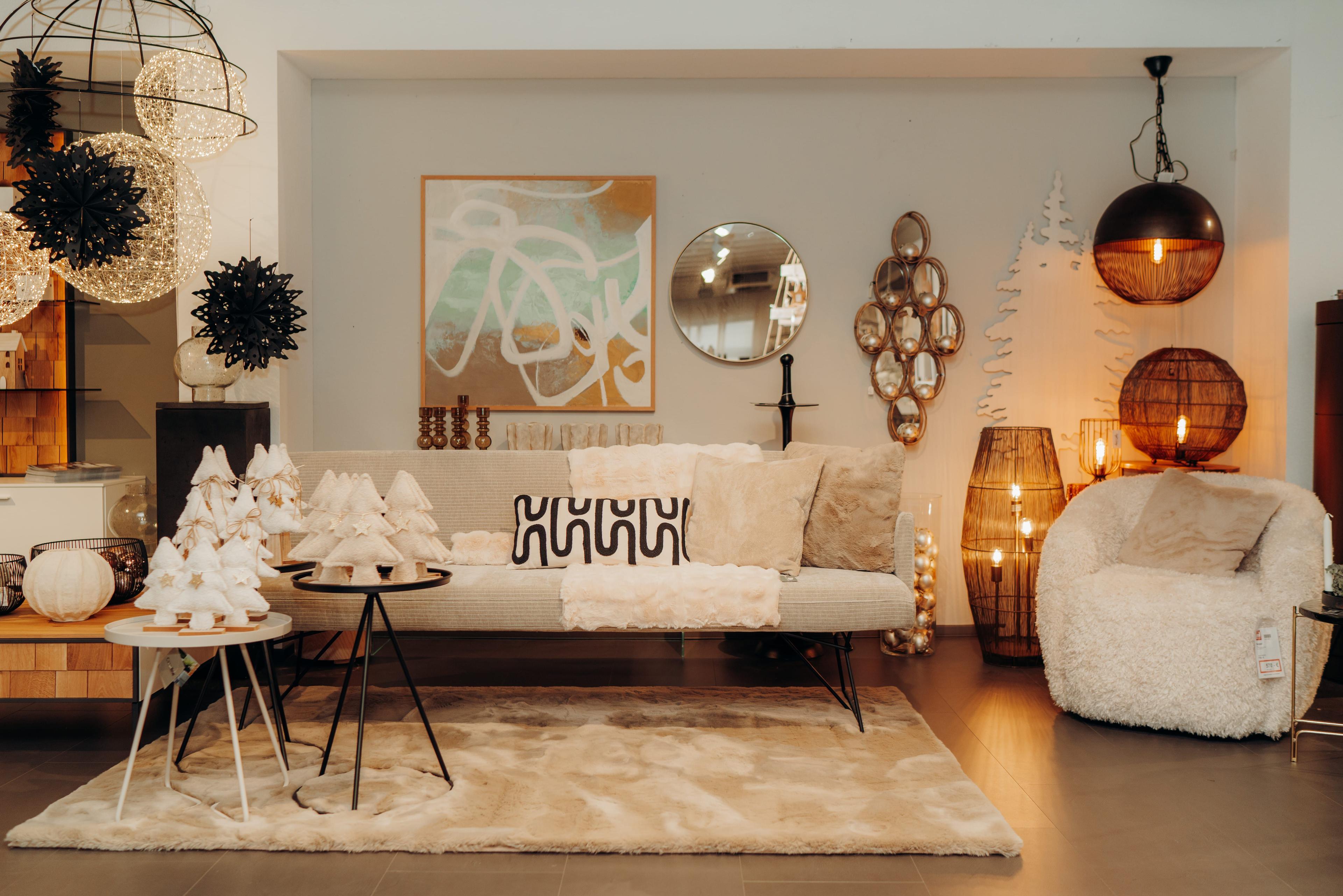Moderne Wohnzimmer-Ausstellung mit beigem Sofa, warmen Holzlampen, dekorativen Weihnachtsbäumen und stilvollen Accessoires bei Möbel Grell.