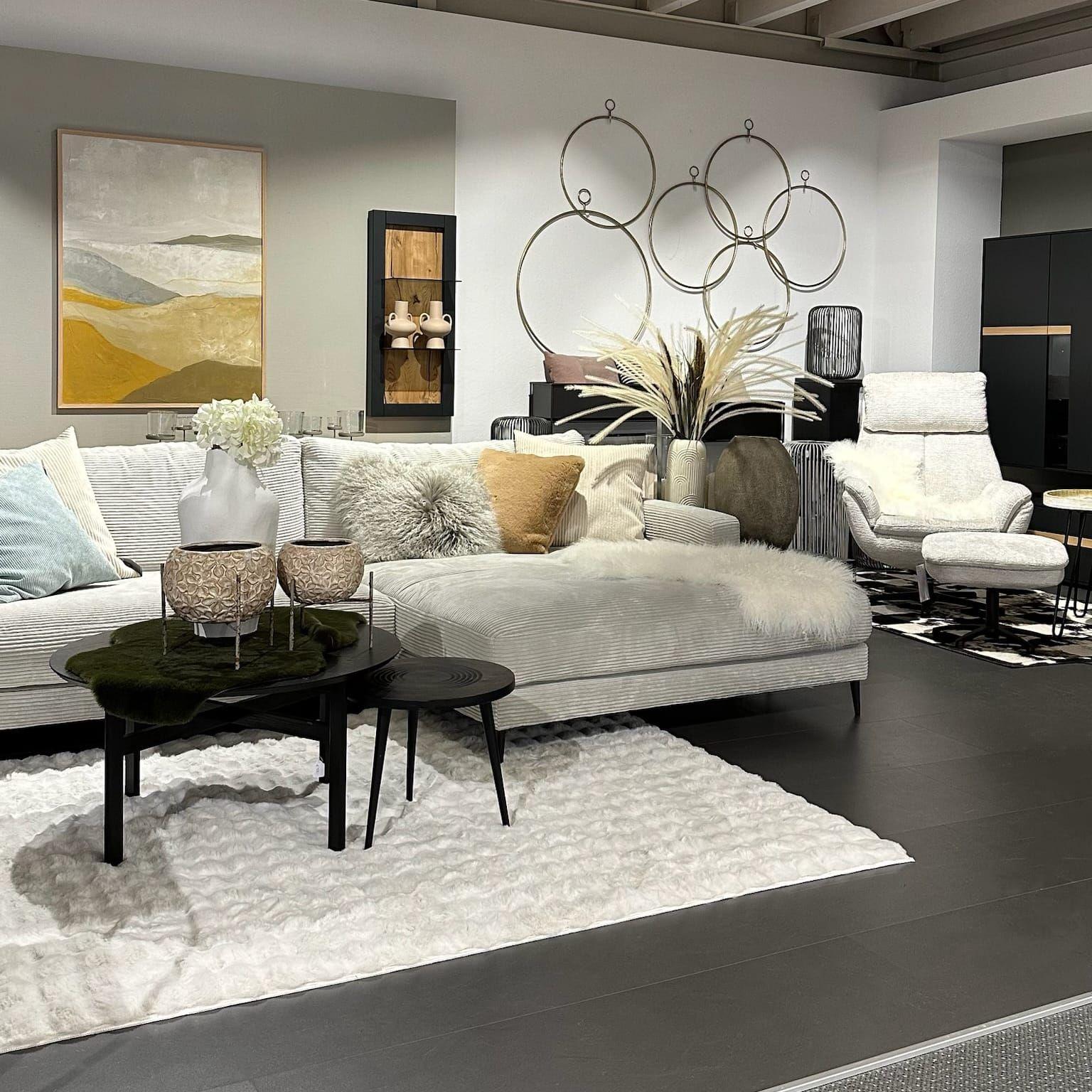 Stilvolles Wohnzimmer mit beigem Cord-Sofa, Wandkreisen und moderner Kunst in harmonischen Erdtönen bei Möbel Grell.