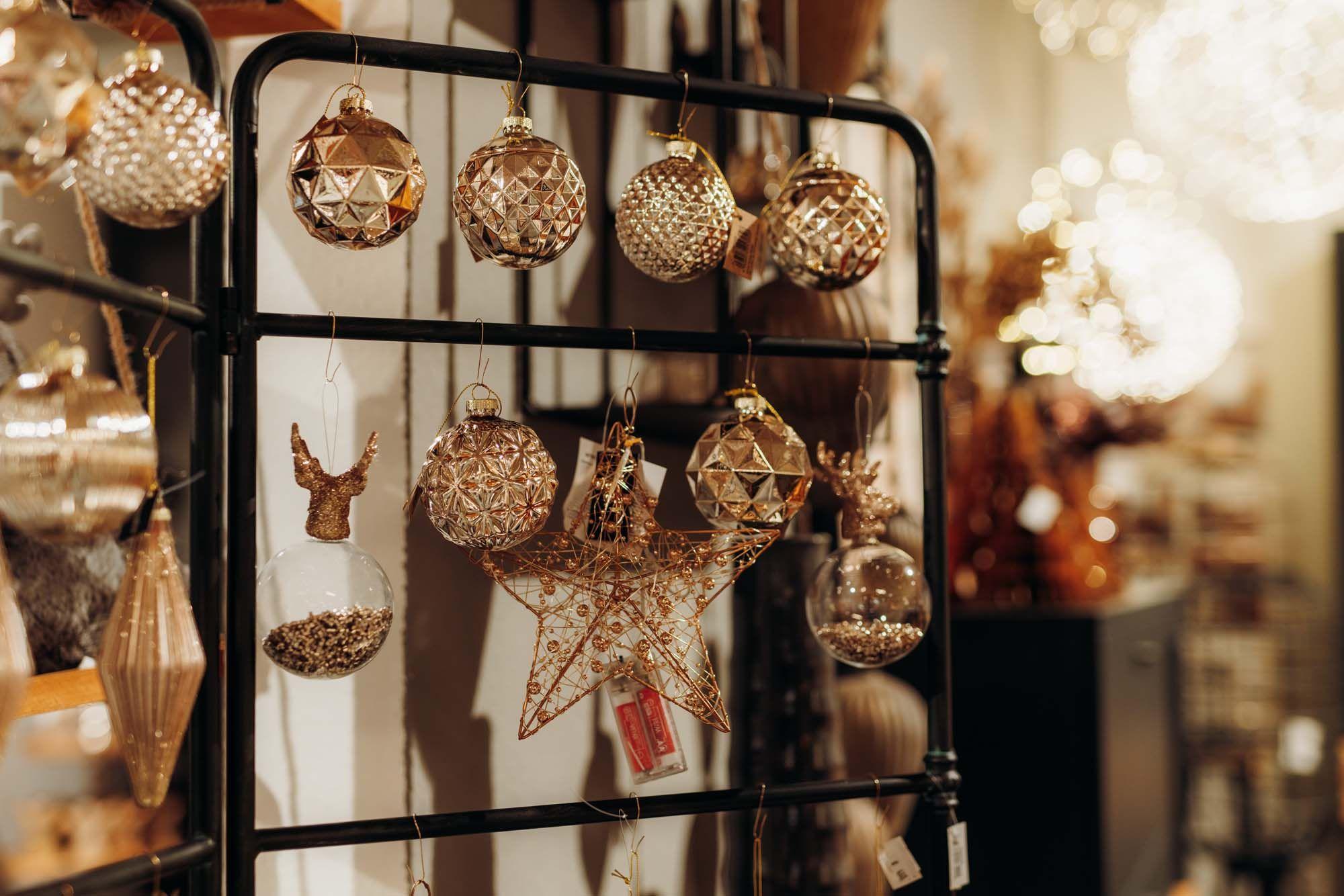 Elegante Christbaumkugeln in Gold und Bronze mit kunstvollem Relief-Design an schwarzem Metallgestell.
