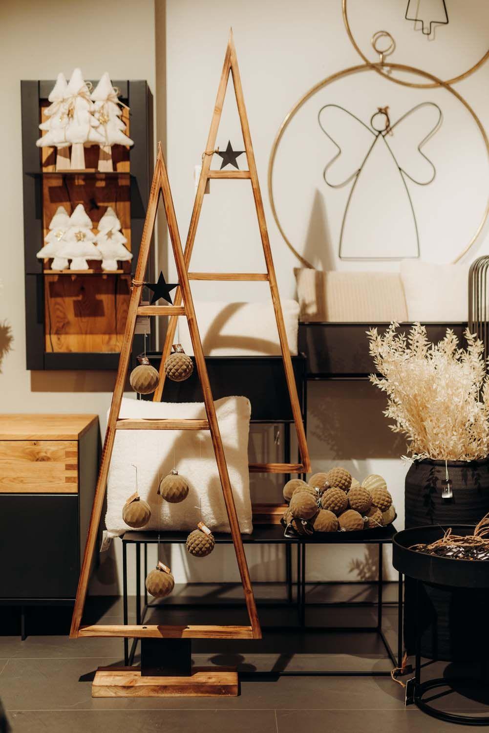 Moderner Holz-Weihnachtsbaum mit goldenen Kugeln, umgeben von stilvollen Wanddeko-Elementen und natürlichen Accessoires.