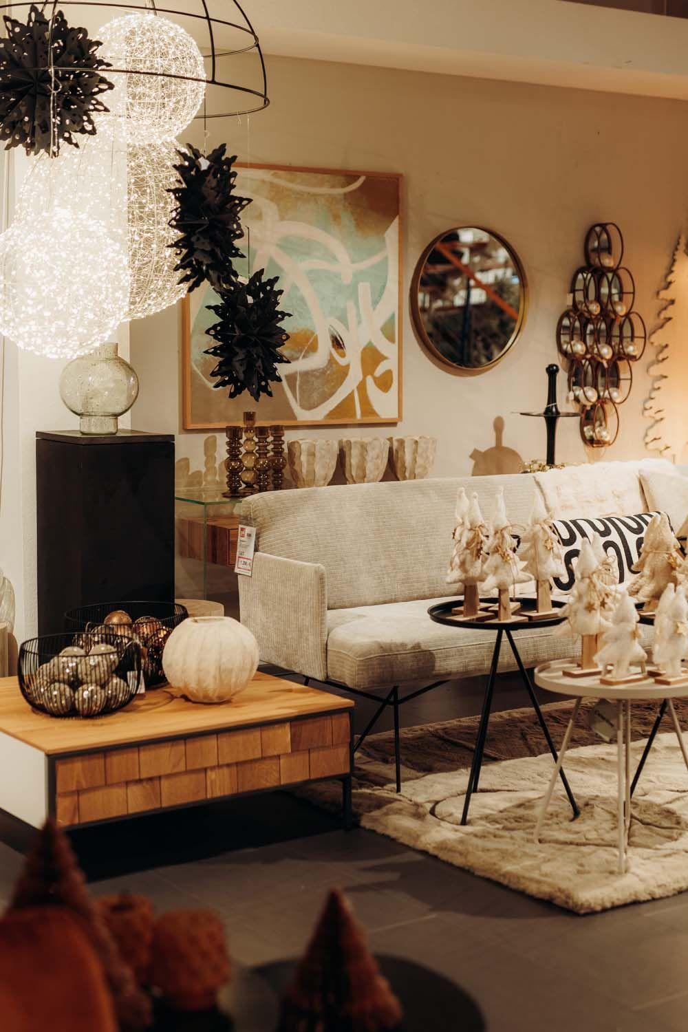 Gemütliche Herbst-Winter-Ausstellung mit beigem Sofa, warmen Textilien und stimmungsvoller Deko in natürlichen Erdtönen.