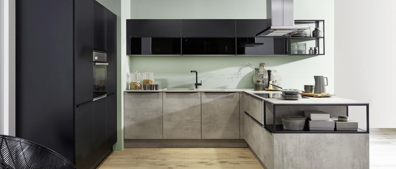 Moderne, minimalistische Küche mit schwarzem Hochglanz-Oberflächen und Betonarbeitsplatten, ergänzt durch offene Regale und eine grüne Wandfarbe, die dem Raum einen frischen Look verleiht.