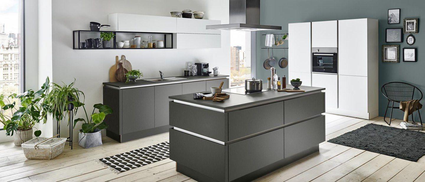 Moderne Kücheninsel in mattem Grau mit weißen Hochschränken, offenen Metallregalen, vielen Pflanzen und skandinavischem Wohnstil auf hellem Holzboden.