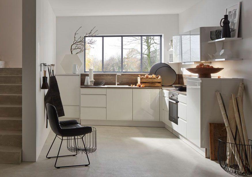 Weiße, minimalistische Küche mit einem großen Fenster und modernen Geräten