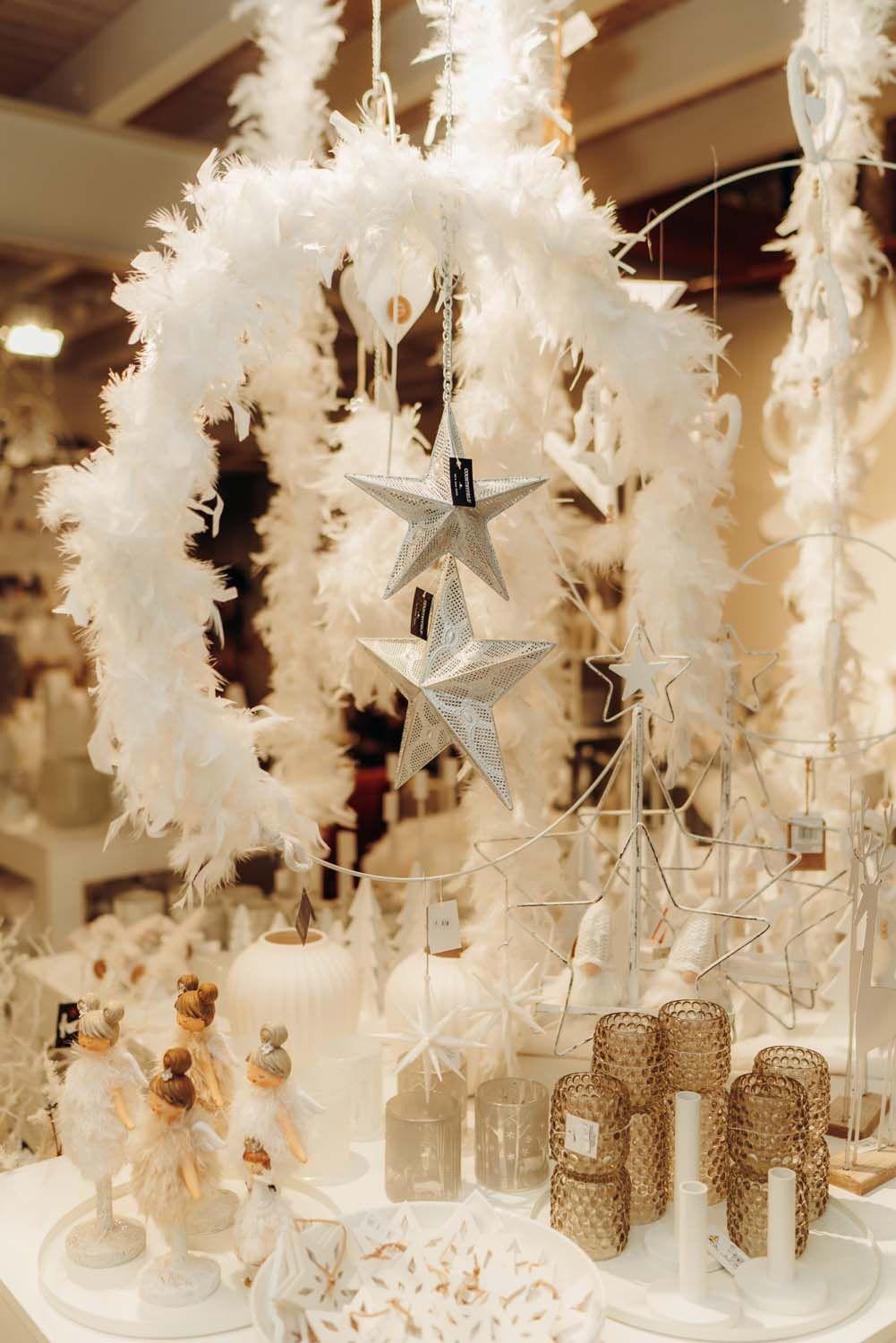 Elegante weiße Federkränze mit silbernen Sternen und goldenen Windlichtern als hochwertige Weihnachtsdeko.