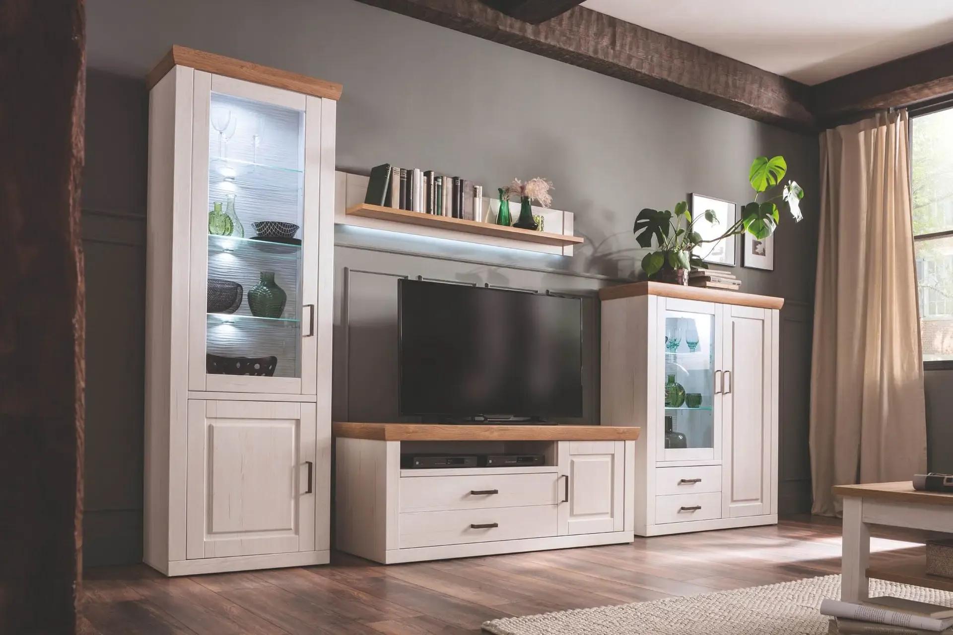 Weiße Wohnwand mit Holzakzenten, TV-Lowboard und beleuchteten Vitrinen in rustikal eingerichtetem Wohnzimmer mit Deckenbalken.