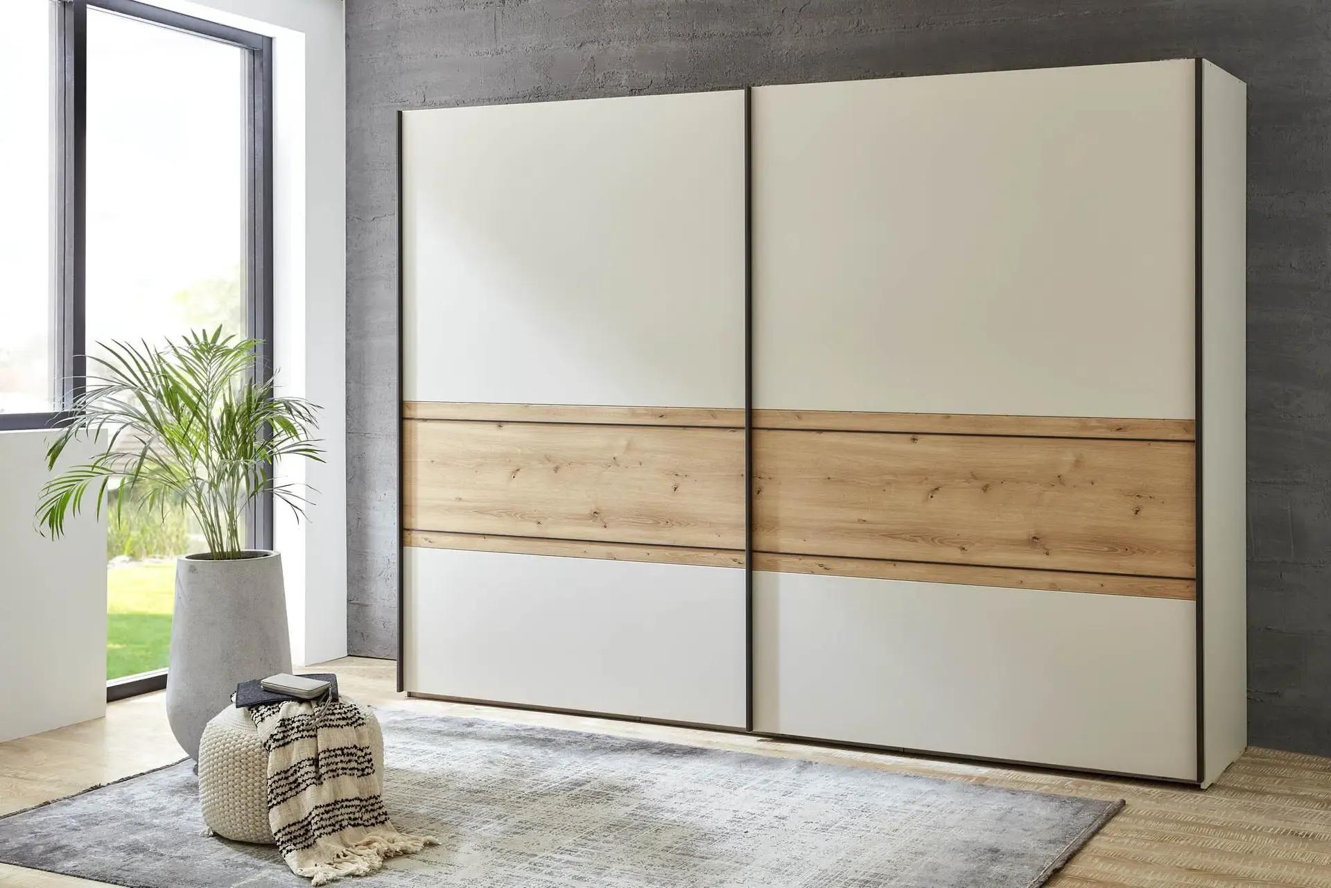 Moderner Kleiderschrank mit Schiebetüren in Cremeweiß und Holzdekor – stilvoller Stauraum im Schlafzimmer mit Teppich, Fensterfront und Zimmerpflanze.