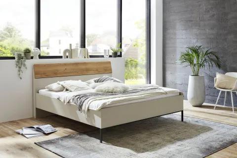 Modernes Bett mit hellem Rahmen und Holz-Kopfteil in einem lichtdurchfluteten Schlafzimmer mit großen Fenstern, Holzboden und dezenten Accessoires.