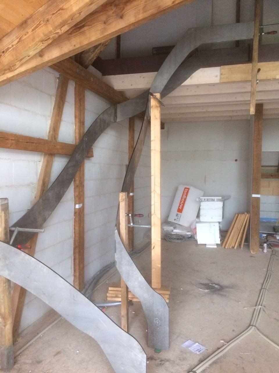 Rohbau-Zustand mit sichtbarer Holzkonstruktion, Treppe im Bau und Baumaterialien im Raum.