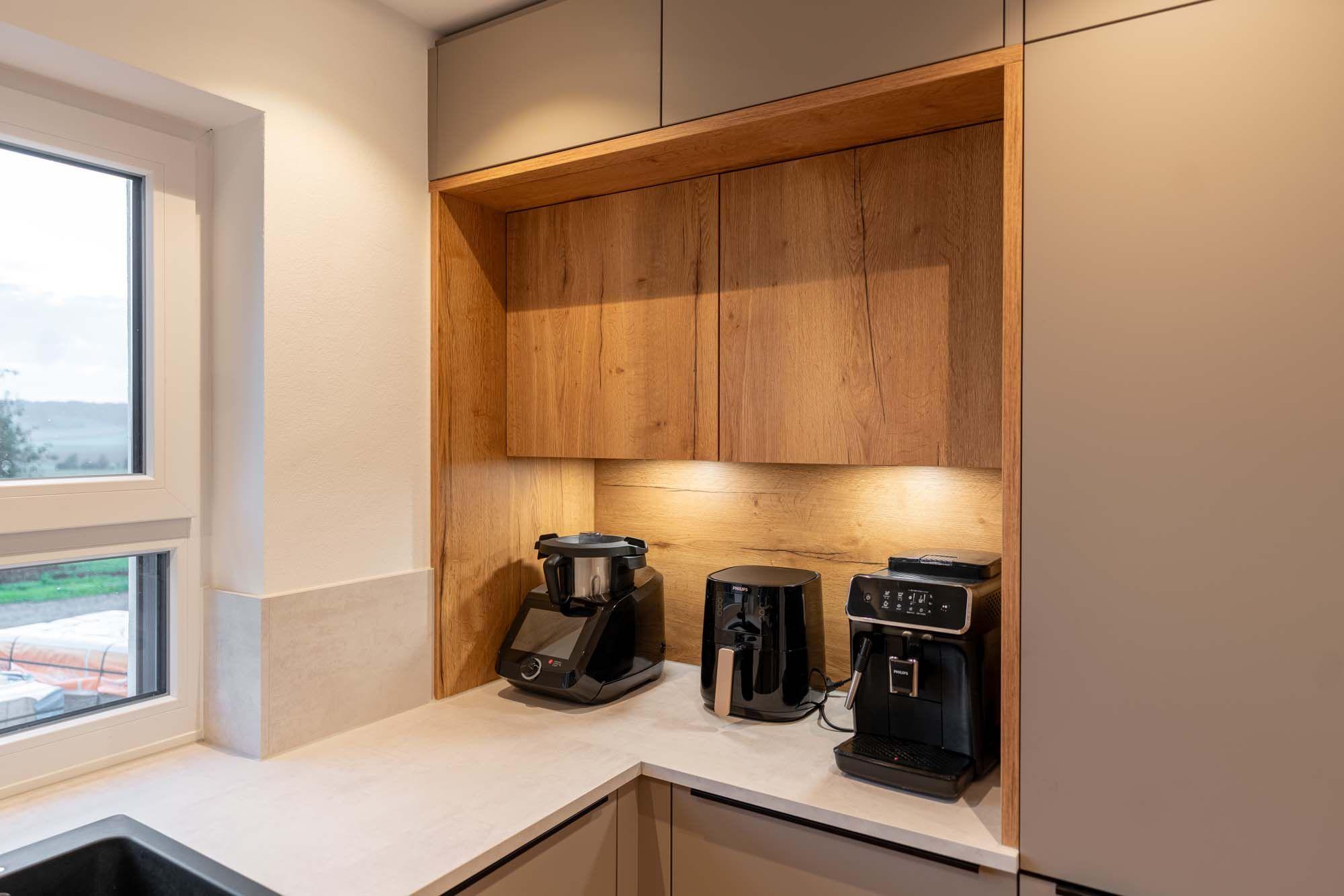Nahaufnahme der beleuchteten Kaffeenische mit Siebträgermaschine, Filterkaffeemaschine und Kaffeevollautomat.