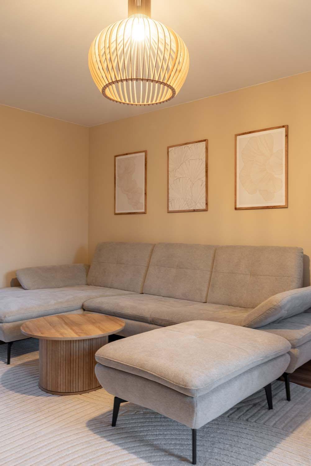 Detailaufnahme des Wohnzimmers mit kugelförmiger Holzpendelleuchte über der Couch.