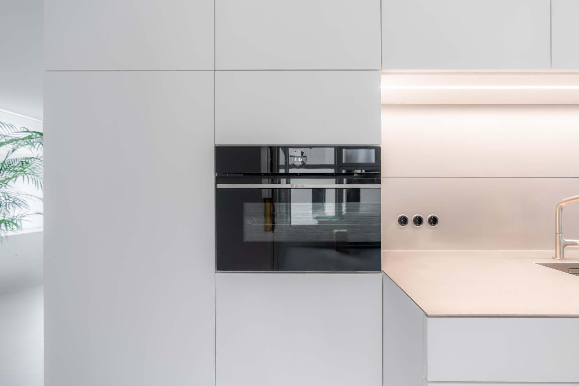 Detailaufnahme eingebauter schwarzer Backöfen mit Glasfront in weißem Hochschrank
