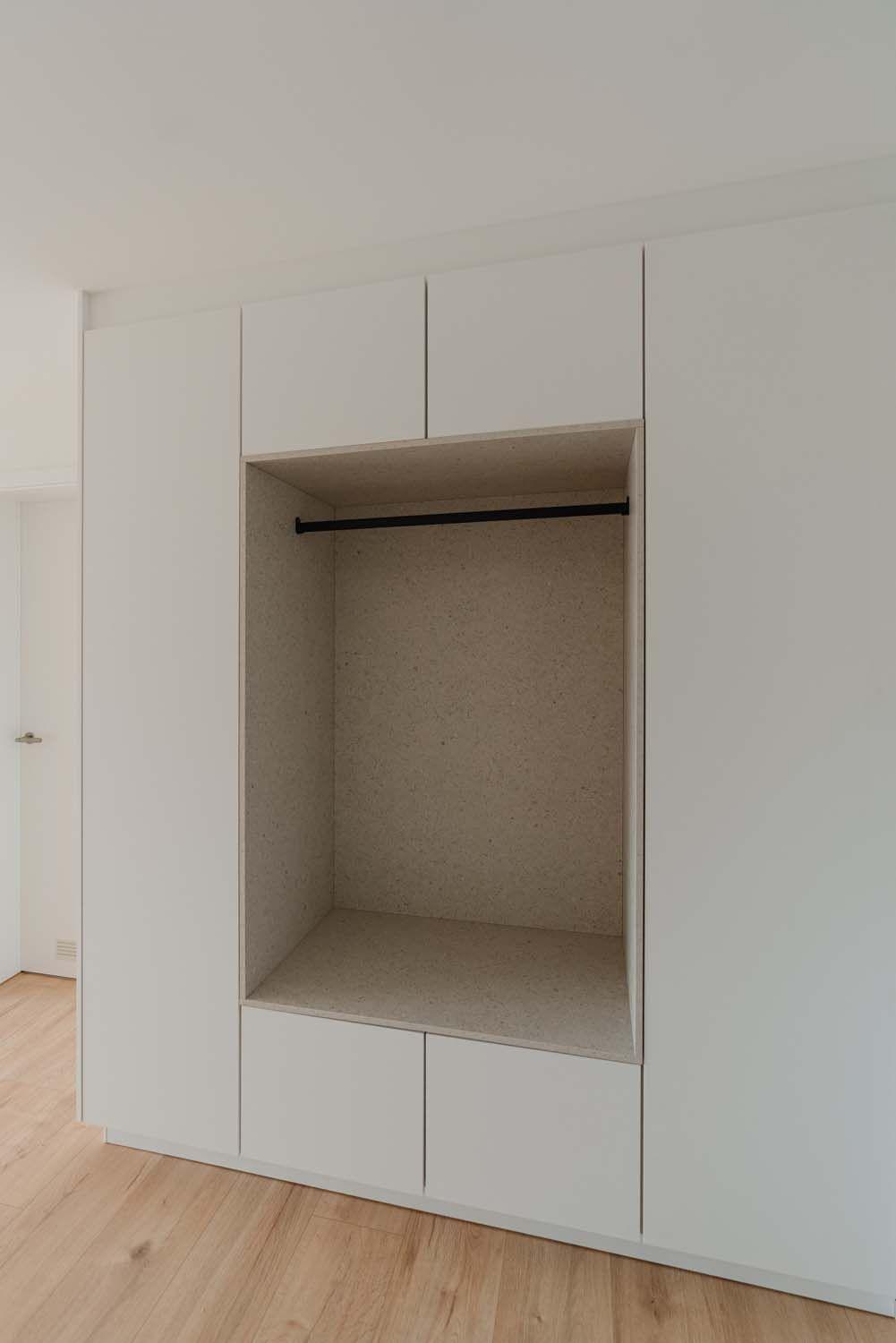 Komplettansicht der Einbaugarderobe mit offener Nische, Sitzelement und seitlichen Schränken.