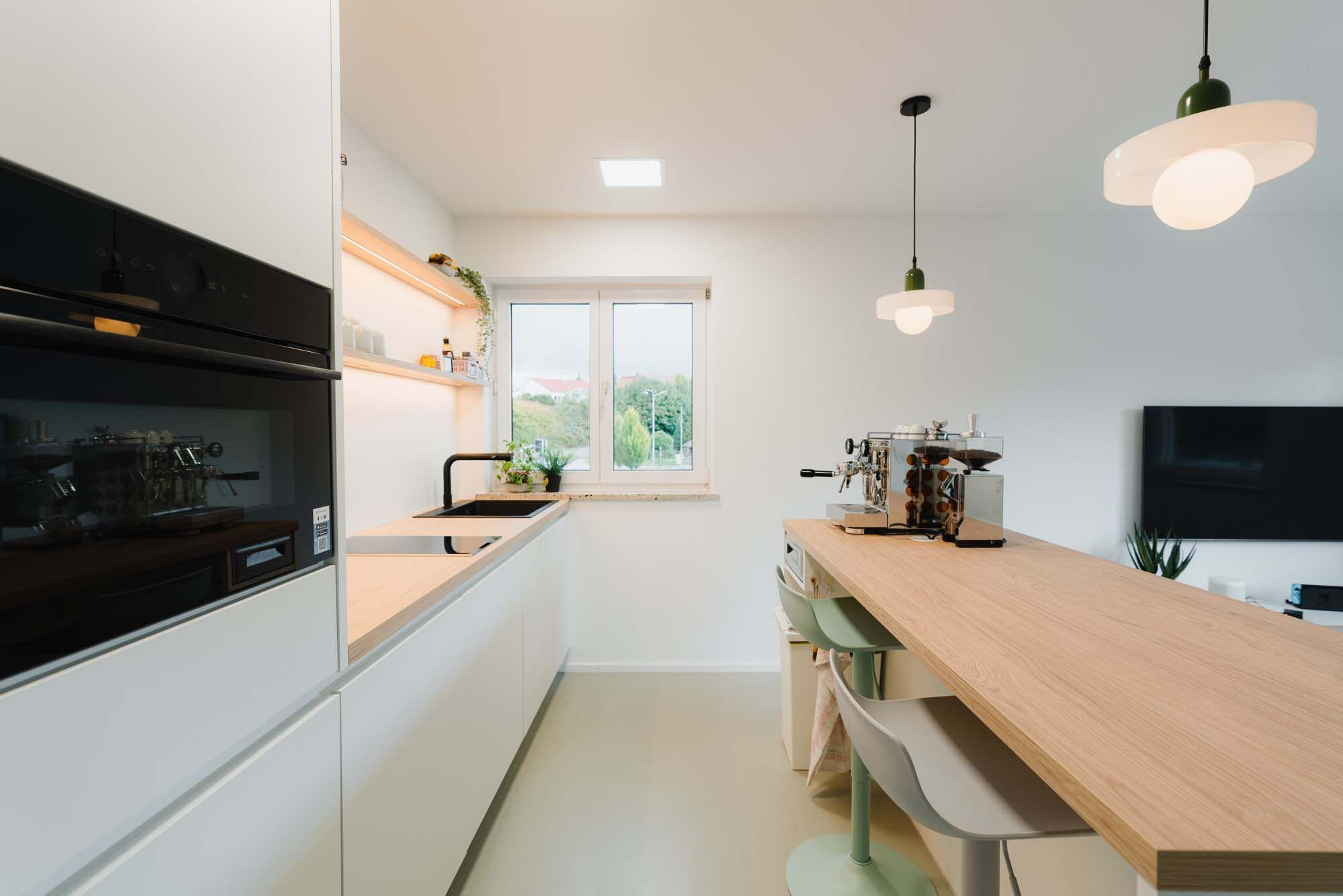 Moderne offene Küche mit langem Eichentisch, Designer-Pendelleuchten und mintgrünen Barhockern.