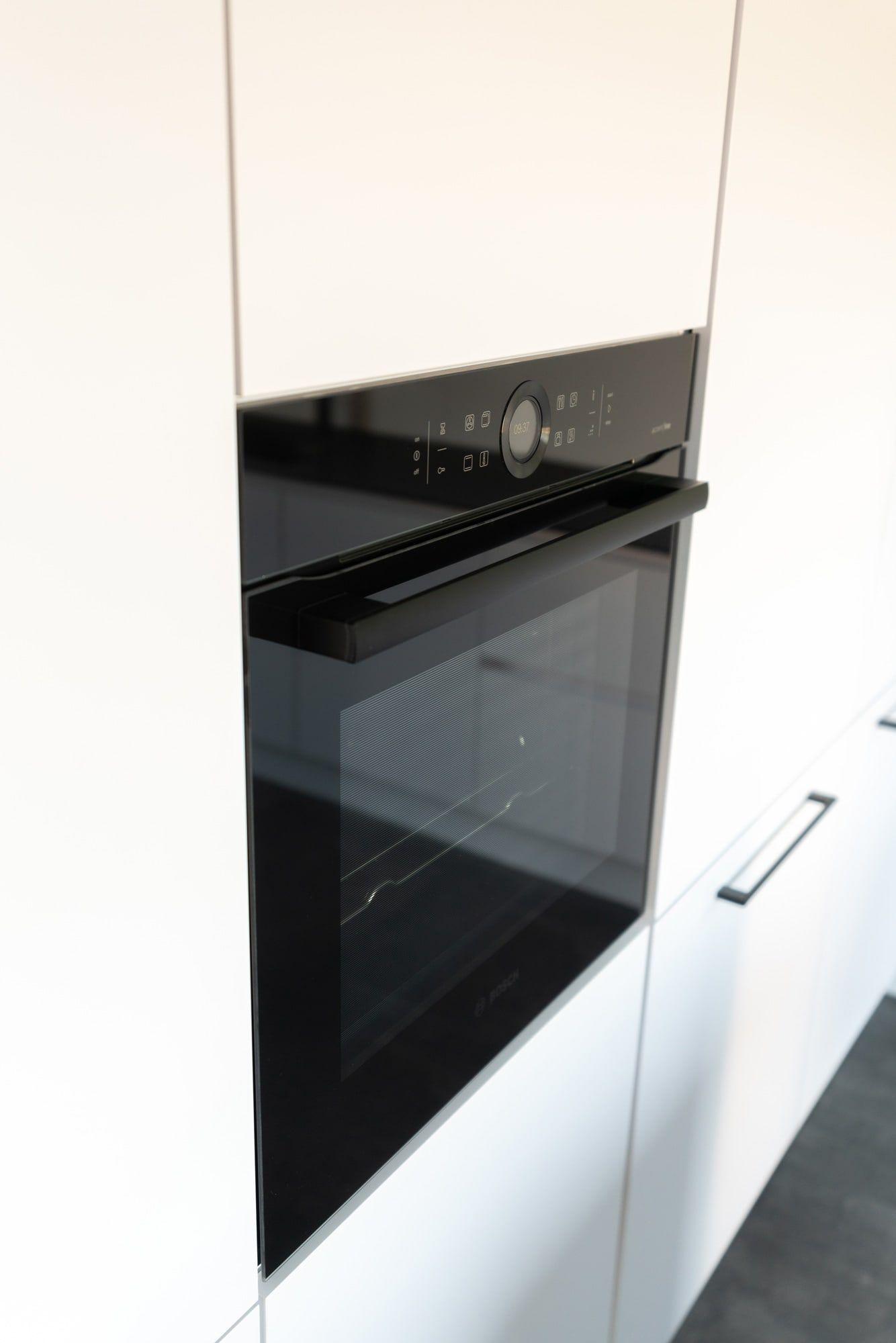 Eingebauter schwarzer Backofen in weißer Hochschrankzeile mit Bedienfeld und Glasfront.