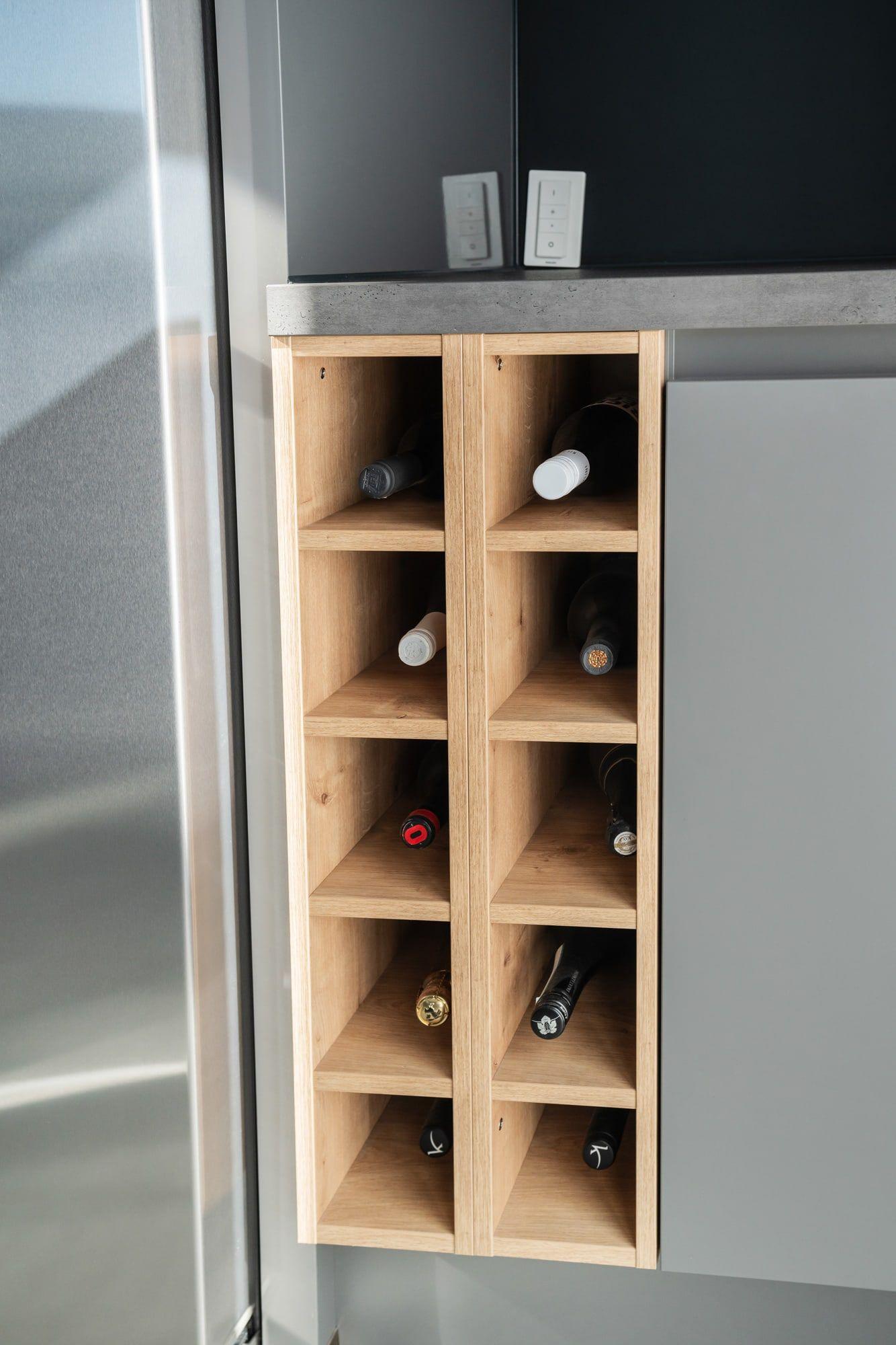 Holz-Weinregal mit zehn Fächern für Weinflaschen, integriert neben einem Edelstahl-Kühlschrank mit grauen Küchenfronten.