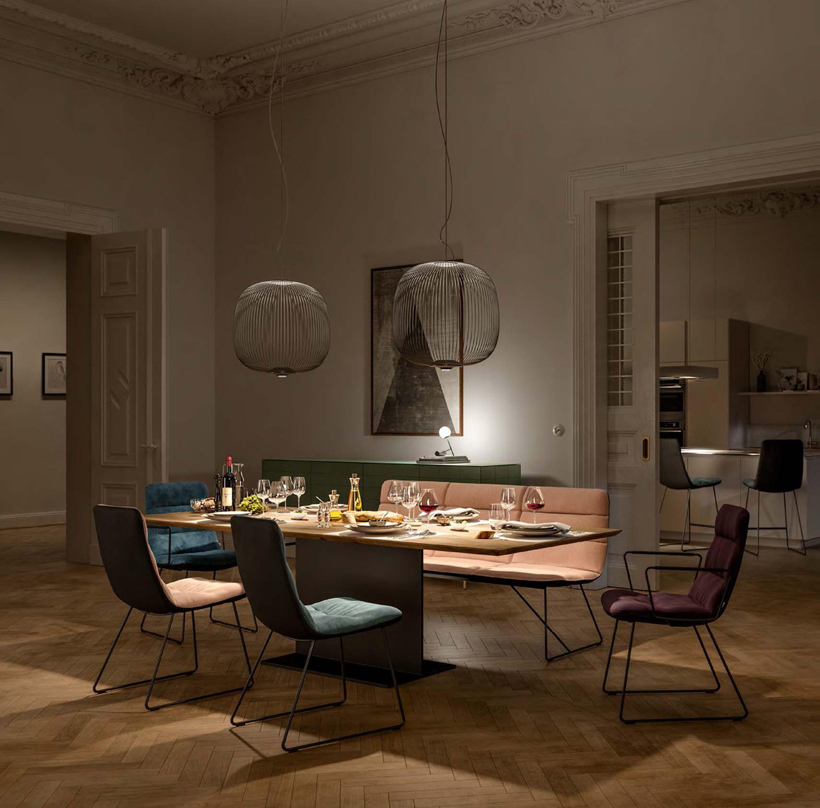 Moderne Essgruppe mit Holztisch, bunten Polsterstühlen und Eckbank unter runden Pendelleuchten in Altbauwohnung mit Stuck und Parkett.