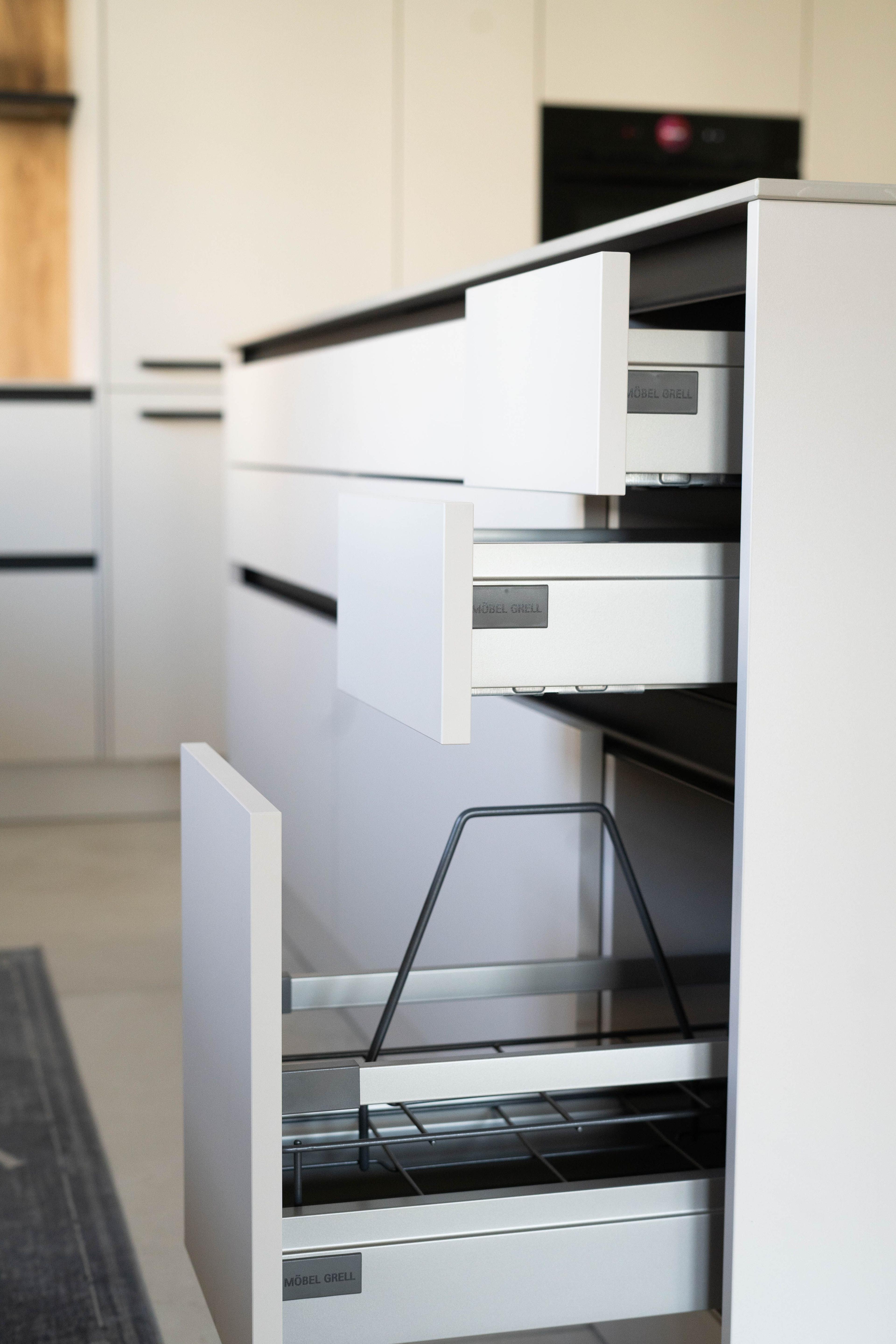 Geöffnete Auszüge an der Kücheninsel mit Innenorganisation und Stauraum für Küchenutensilien.