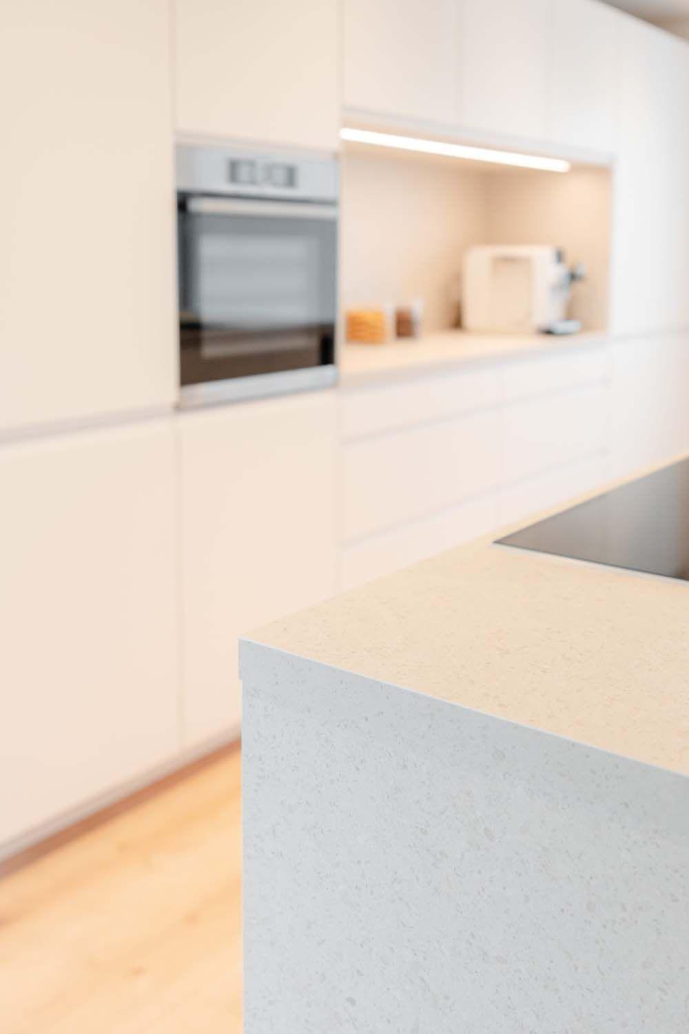 Unscharfer Blick über die Kücheninsel zur Küchenzeile mit eingebautem Backofen