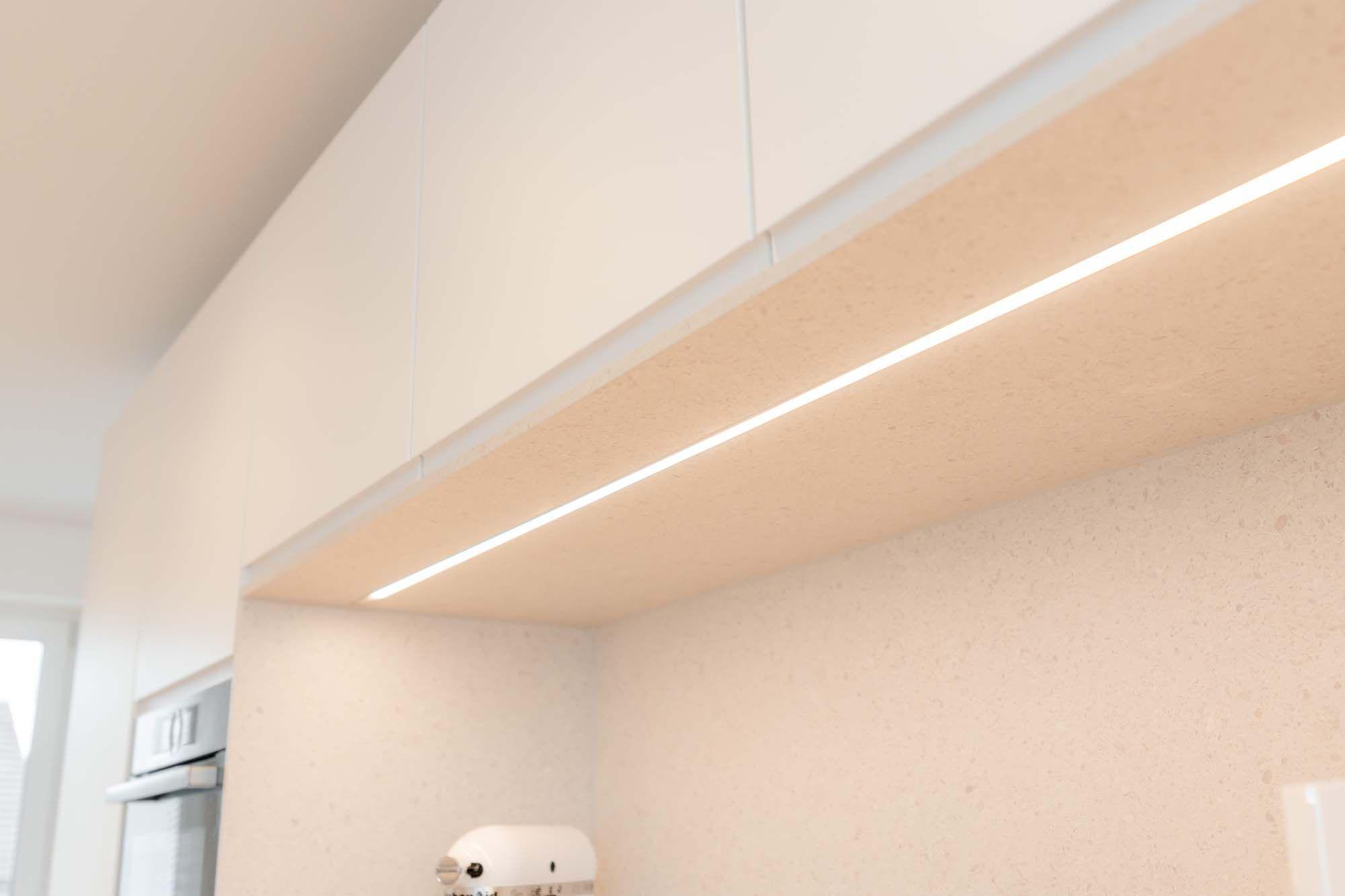 LED-Unterbauleuchten an weißen Oberschränken mit warmweißem Licht.
