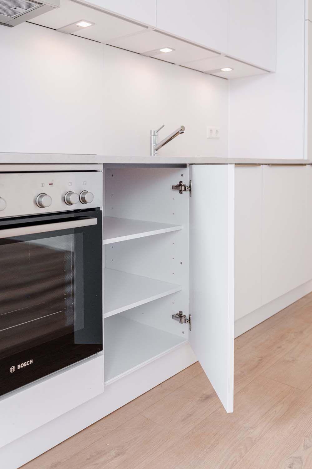 Geöffneter Küchenschrank neben Bosch-Backofen mit weißen Einlegeböden und verstellbaren Scharnieren.