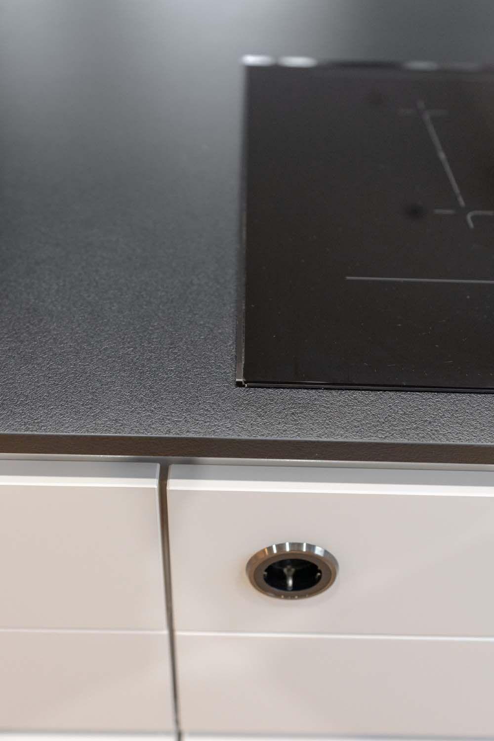 Nahaufnahme der schwarzen Arbeitsplatte mit integriertem Ceranfeld.