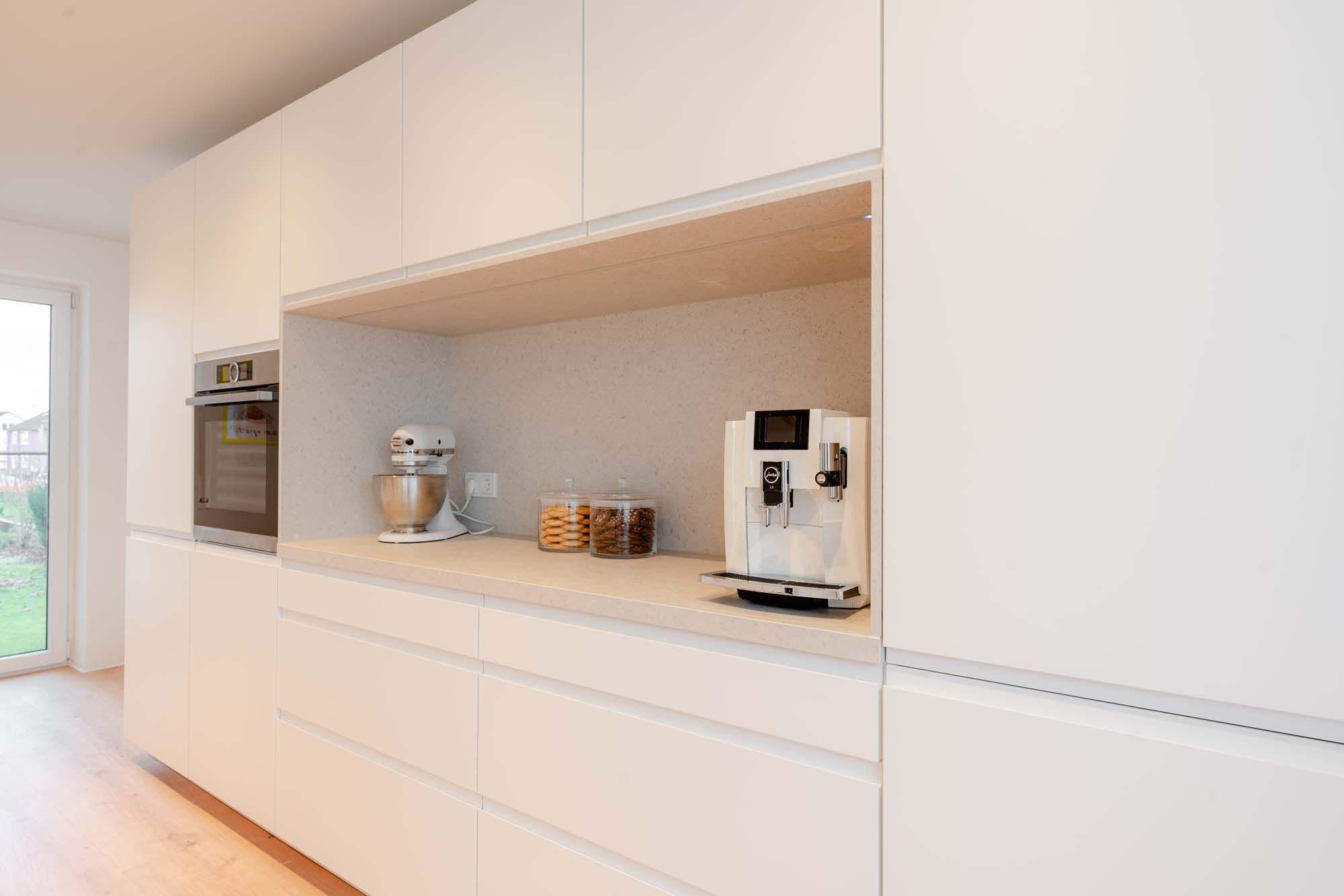 Eingebaute Küchenzeile mit Nische für Küchenmaschine, Kaffeevollautomat und offener Stauraum mit Holzoptik.