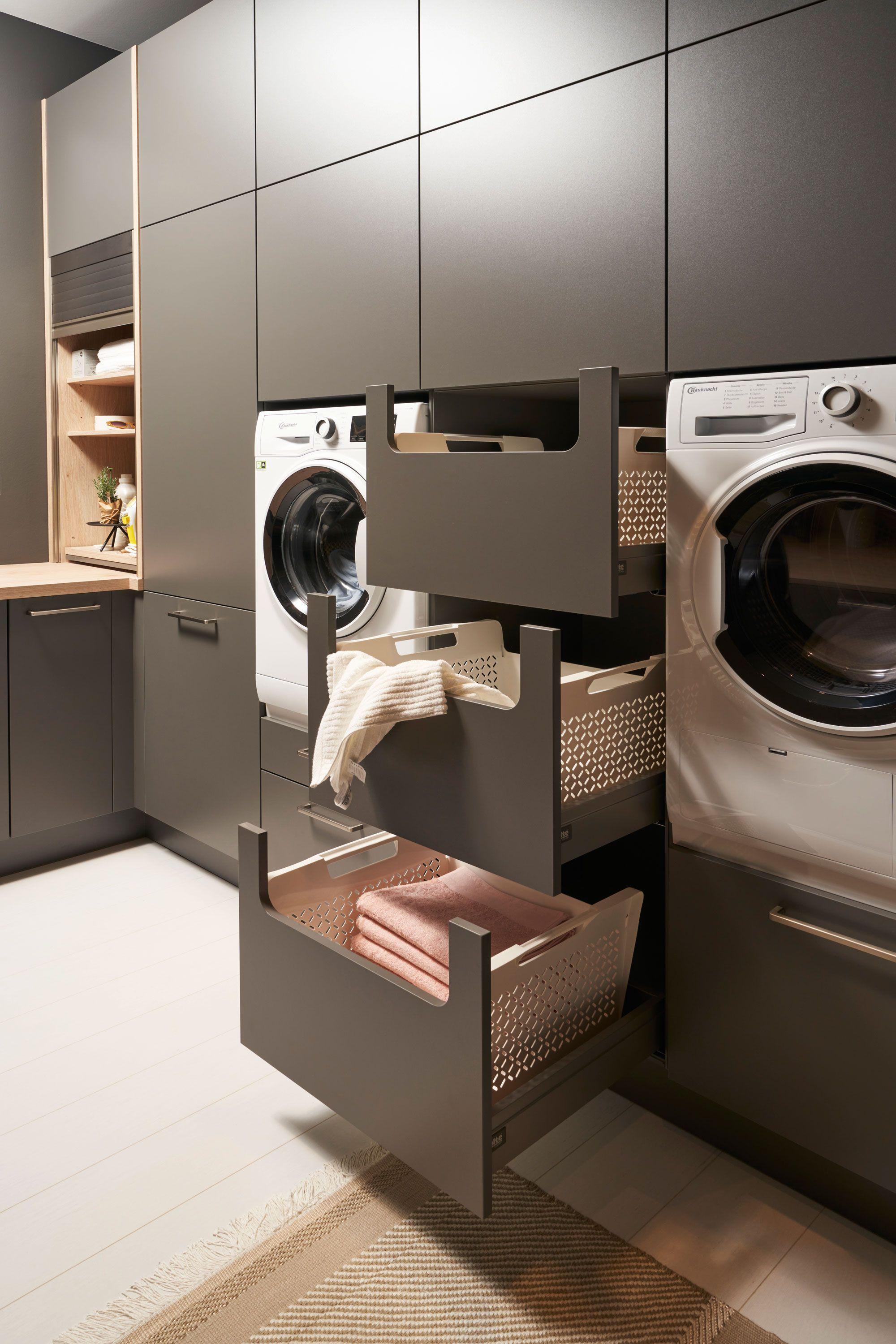 Hauswirtschaftsraum mit ausziehbaren Wäschekörben in anthrazitfarbenen Schränken zwischen Waschmaschine und Trockner.