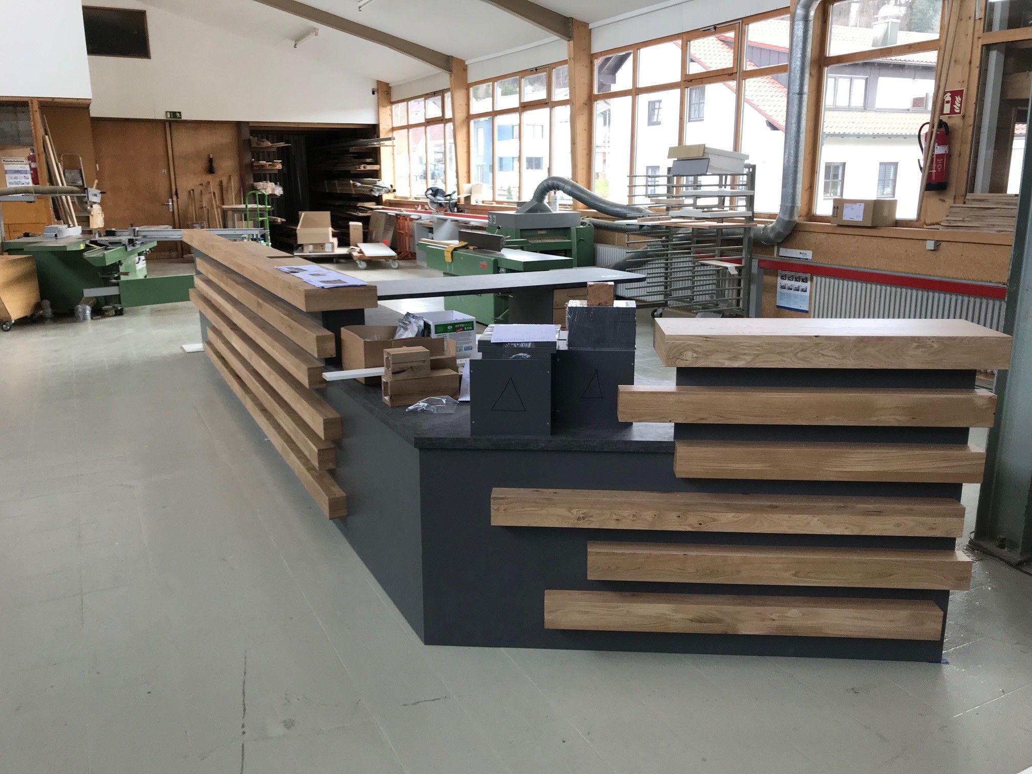 Schreinerei-Werkstatt mit fertiggestellten Holztreppen als Ausstellungsstücke, grünen Maschinen und großen Fenstern zur Straße.