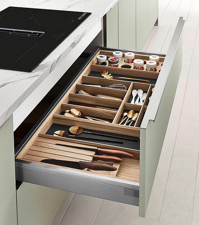 Geöffnete Küchenschublade mit organisiertem Holz-Besteckeinsatz, verschiedenen Küchenutensilien und Gewürzdosen neben einem schwarzen Kochfeld.WiederholenClaude kann Fehler machen. Bitte überprüfen Sie die Antworten.