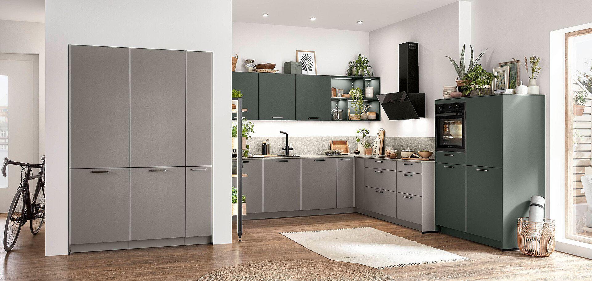 Elegante, minimalistische Küche in grauen und grünen Tönen, ergänzt durch moderne Geräte und offene Regale für Pflanzen und Deko.
