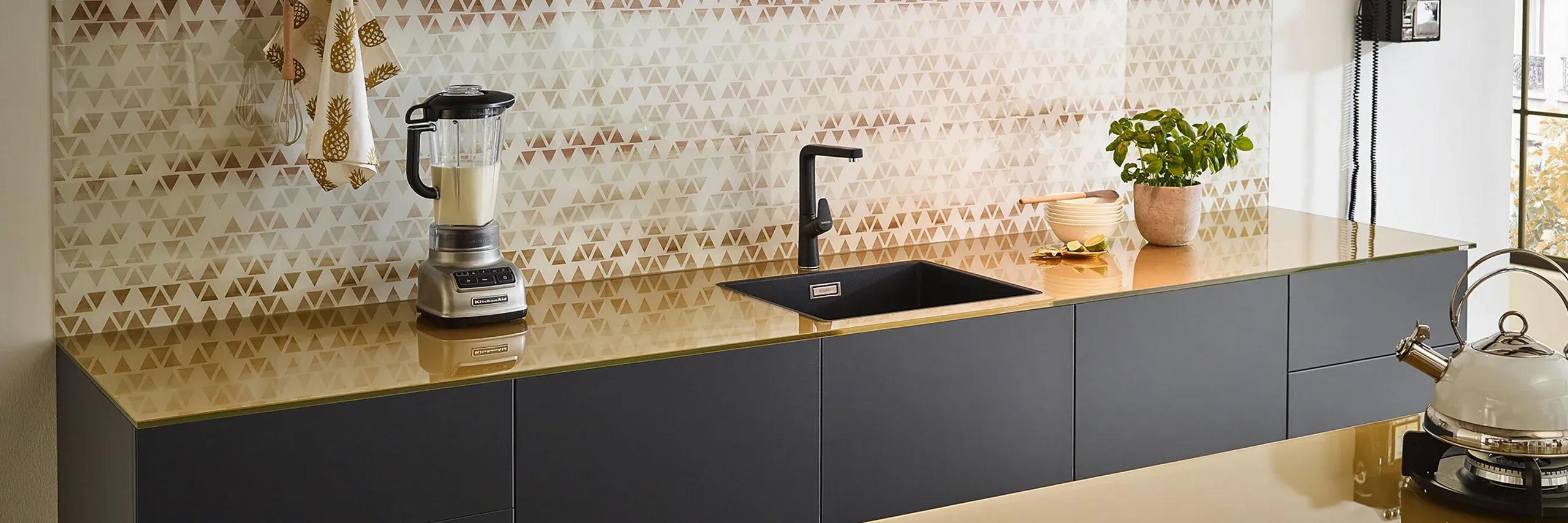 Goldene Glas-Arbeitsplatte mit geometrischer Küchenrückwand - edle Arbeitsplatten von Möbel Grell