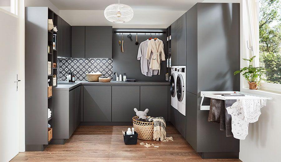 Moderner Hauswirtschaftsraum in Anthrazit mit gemusterter Rückwand, Garderobenstange, Waschmaschine und stilvoller Pendelleuchte.