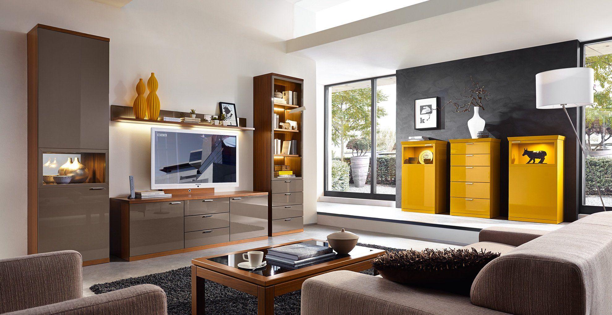 Moderne Wohnwand in Grau und Holz mit TV-Bereich, kombiniert mit gelben Hochglanz-Sideboards vor dunkler Akzentwand in zeitgenössischem Wohnzimmer.