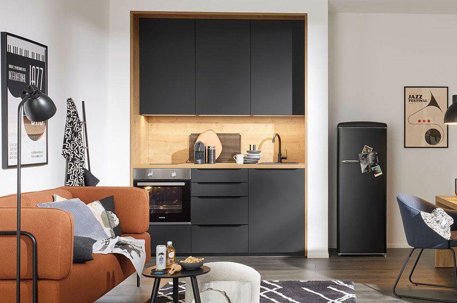 Komfortable Studentenwohnung mit einer eleganten, schwarzen Küchenzeile, einem Kühlschrank im Retro-Stil, einer gemütlichen Couch und einem Schreibtischbereich.