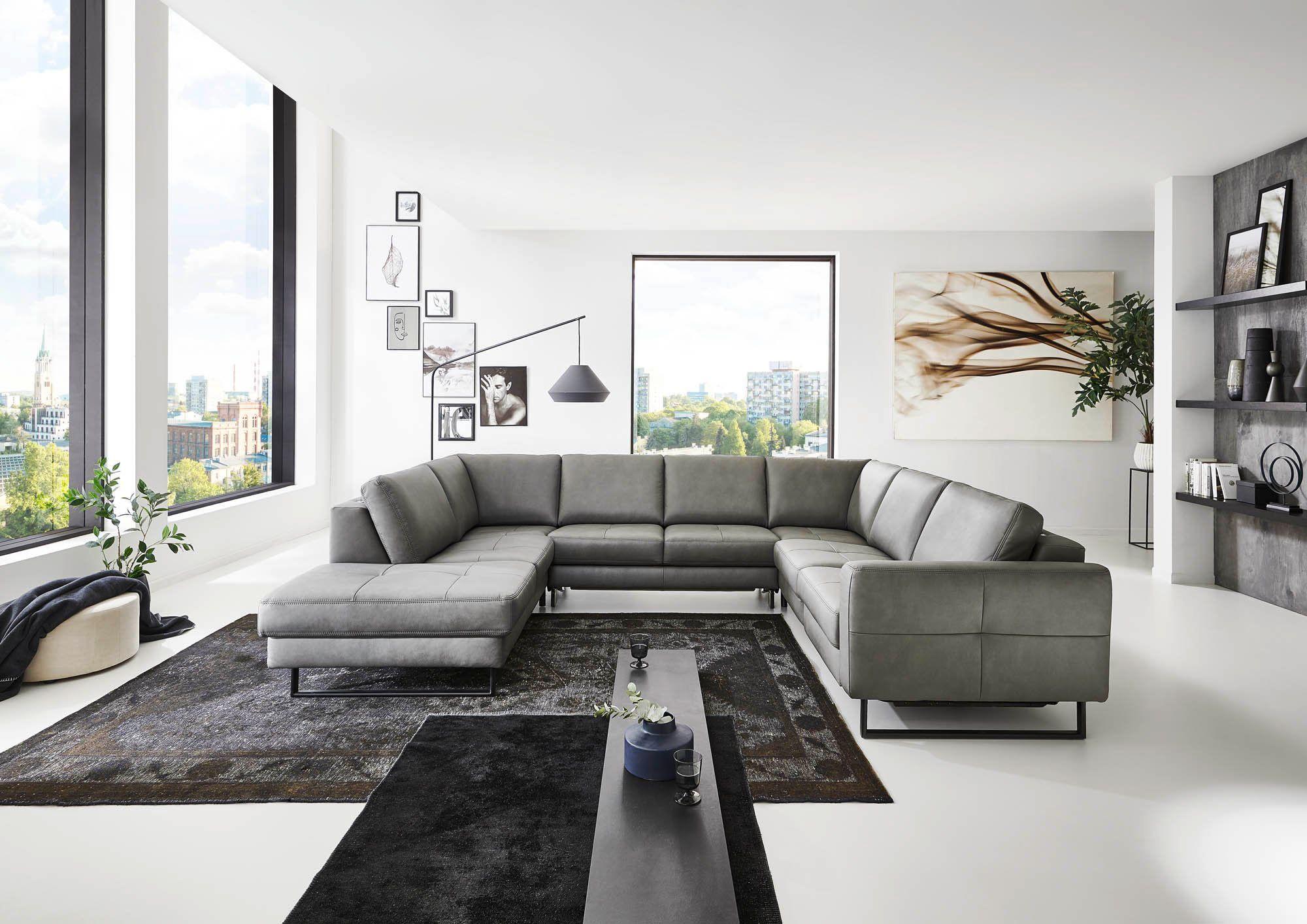 Große graue Leder-Wohnlandschaft in U-Form mit schwarzem Couchtisch vor Panoramafenstern in modernem Loft.