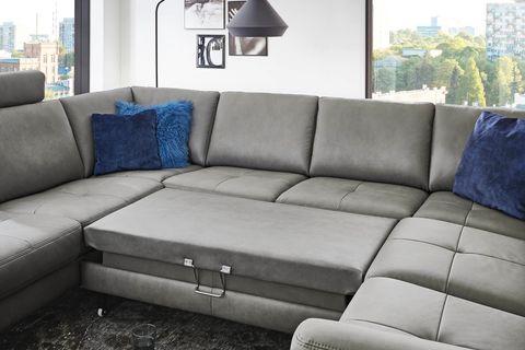 Große graue Leder-Wohnlandschaft in U-Form mit schwarzem Couchtisch vor Panoramafenstern in modernem Loft.