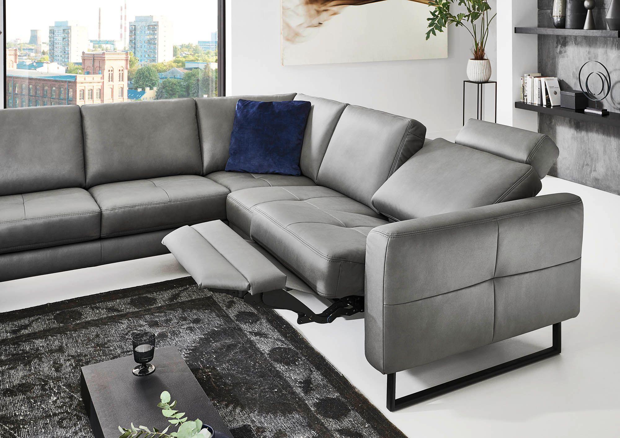 Graues Ledersofa mit ausgefahrener Relaxfunktion und Fußstütze vor Stadtpanorama.