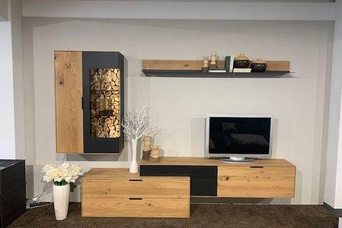 Moderne Wohnwand aus Holz und Anthrazit mit integriertem Brennholzfach und TV-Bereich.