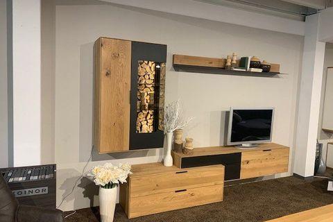 Moderne Wohnwand aus Holz und Anthrazit mit integriertem Brennholzfach und TV-Bereich.