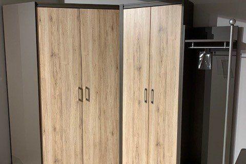 Eckschrank aus hellem Eichenholz mit anthrazitfarbenen Seiten unter Dachschräge in Möbelausstellung.