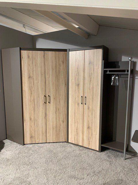 Eckschrank aus hellem Eichenholz mit anthrazitfarbenen Seiten unter Dachschräge in Möbelausstellung.