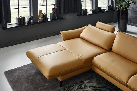 Cognacfarbene Leder-Eckcouch mit Chaiselongue und schwarzem Couchtisch in Industrial-Loft mit Betonwand.
