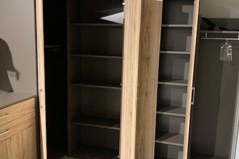 Eckschrank aus hellem Eichenholz mit anthrazitfarbenen Seiten unter Dachschräge in Möbelausstellung.