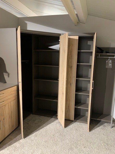 Geöffneter Eckschrank zeigt Innenaufteilung mit mehreren Fächern und Regalbrettern in beiden Schrankteilen.