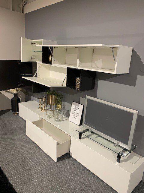 Wohnwand-System mit geöffneten Klappen und Schubladen, zeigt flexible TV-Halterung und Stauraumlösungen.