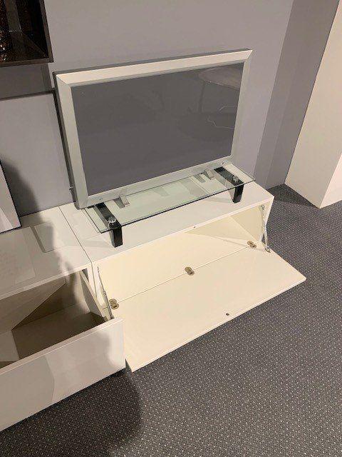 TV-Lowboard mit ausklappbarer Glasplatte und geöffneten weißen Türen zeigt Innenausstattung
